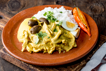 MEXICAN AND PERUVIAN CUISINE. Aji de gallina. Chicken aji de gallina with olives egg and rice on clay plate. Tipical peruvian and mexican dish