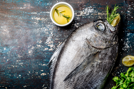 Food background with raw fresh fish reineta, herbs, olil and lemon. Top view