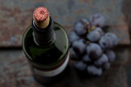 Top view of red wine bottle. Macro selective focus on wine cork. Wine bottle, wine glass and grape on vintage background. Copi space, wine conceptの写真素材