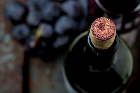 Top view of red wine bottle. Macro selective focus on wine cork. Wine bottle, wine glass and grape on vintage background. Copi space, wine concept