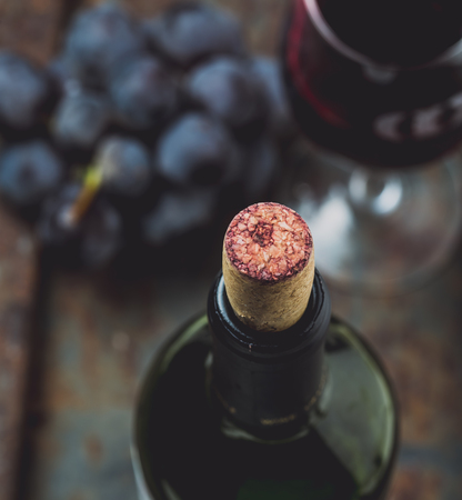 Top view of red wine bottle. Macro selective focus on wine cork. Wine bottle, wine glass and grape on vintage background. Copi space, wine conceptの写真素材