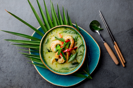 THAI SHRIMPS GREEN CURRY. Thailand tradition green curry soup with shrimps prawns and coconut milk. Green Curry in blue plate on gray backgroundの写真素材