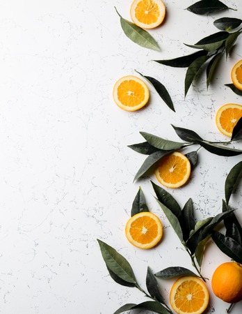 Flat lay orange slices, orange tree eaves and empty plate. Copy space. top view