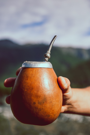 Man holding calabash yerba mate in nature. Travel and adventure concept. Latin American drink yerba mateの写真素材