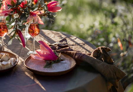 Beautiful table setting in garden on sunset light. Table decorated with magnolia flowers under...
