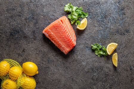 Food background with fresh salmon filet steak, lemon and coriander