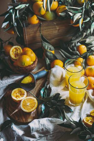 Orange harvest concept. Table with orange juice and box of oranges and orange tree leaves.の写真素材