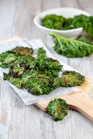 Homemade Green Kale Chips on vintage newspapper, white backgroundの写真素材