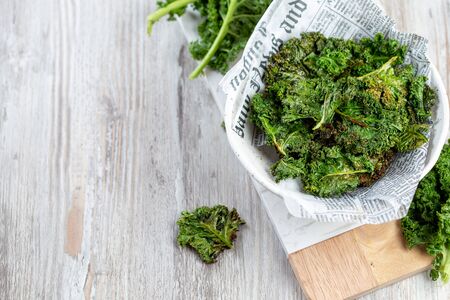 Homemade Green Kale Chips on vintage newspapper, white backgroundの写真素材