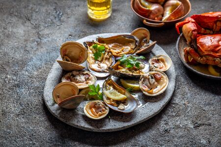 Raw seafood, crabs, clams and mussels shellfish with lemon and cilantro on gray plate.の写真素材