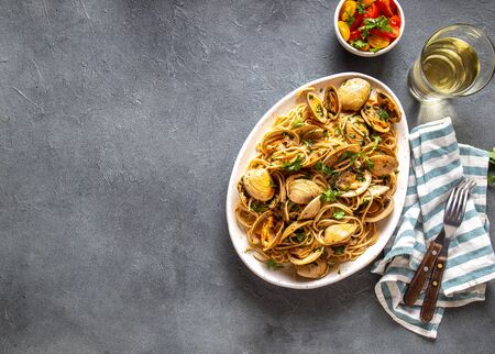 Seafood Pasta. ITALIAN SPAGHETTI ALLE VONGOLE. Clams spaghetti on white plate with white wine, gray background. Top view.の写真素材