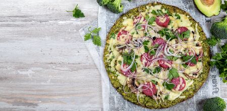 Crust Broccoli base low carbs keto pizza with salami, avocado on vintage newspapper. Top viewの写真素材