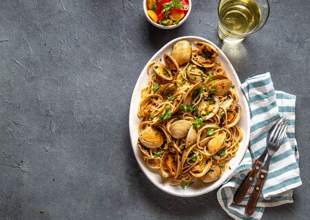 Seafood Pasta. ITALIAN SPAGHETTI ALLE VONGOLE. Clams spaghetti on white plate with white wine, gray background. Top view.の写真素材