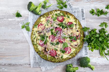 Crust Broccoli base low carbs keto pizza with salami, avocado on vintage newspapper. Top viewの写真素材