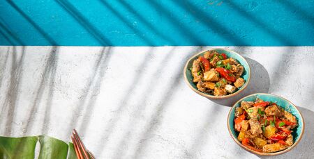 Hawaiian pinapple chicken in blue bowls on white background. Sunlight effect.の写真素材