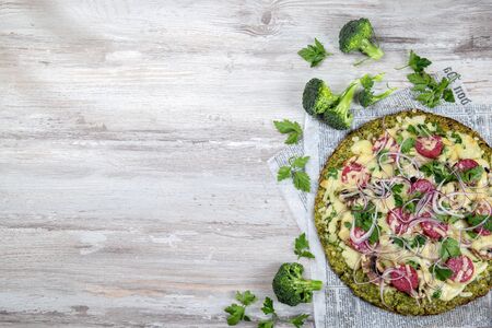 Crust Broccoli base low carbs keto pizza with salami, avocado on vintage newspapper. Top view.の写真素材