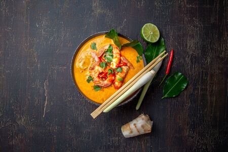 Shrimps Tom Yam Kung in grey bowl with thai spices on autentic tray top view, wooden backgroundの写真素材