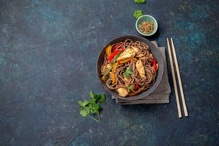 Japanese dish buckwheat soba noodles with chicken and vegetables carrot, bell pepper and green beans in grey bowl, top view, copy space.の写真素材