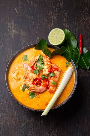 Shrimps Tom Yam Kung in grey bowl with thai spices on autentic tray top view, wooden backgroundの写真素材