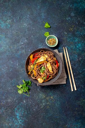 Japanese dish buckwheat soba noodles with chicken and vegetables carrot, bell pepper and green beans in grey bowl, top view, copy space.の写真素材