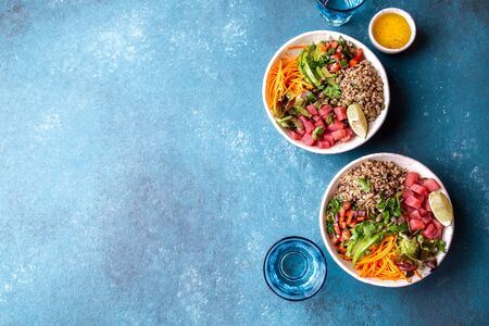 Raw Tuna quinoa health salad with vegetables on blue background.