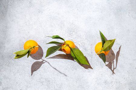 Whole oranges witl orange tree leaves on white background sunlight. top view, flat lay, summer and healthy concept.の写真素材