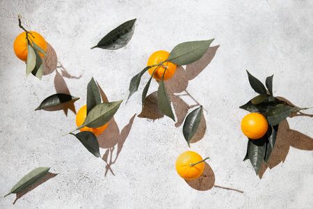 Whole oranges witl orange tree leaves on white background around empty plate. top view, flat lay, summer and healthy concept. Mockup.の写真素材