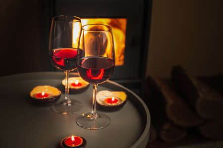Two glasses of red wine front of fireplace. Romantic lightの写真素材