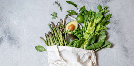 Healthy food ingredients green vegetables and fruits in eco linen bag, zero waste and clean eating concept. gray backgroundの写真素材