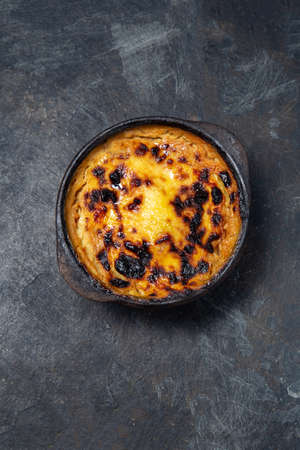 Chilean food. Traditional Pastel de Choclo corn pie. Beef meat with onion, chicken and egg covered with ground corn in clay bowl, top viewの写真素材
