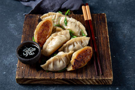 Asian dumplings Gyoza potstickers on old wooden board. Top view, copy spaceの写真素材