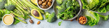 Vegetarian green ingredients on gray background. Vegetarian food - vegetables, greens, avocado, oil...