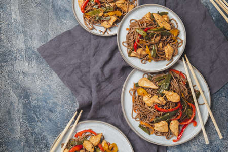 Japanese dish buckwheat soba noodles with chicken and vegetables carrot, bell pepper and green beans in wok on dark blue backgroundの写真素材