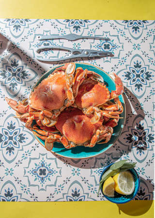 Cooked crab on blue plate, lemons, rose wine on table, sunlight immitationの写真素材