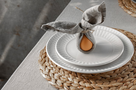 Festive Easter table setting. Funny Easter bunny made of egg and linen napkin on plate. Gray background.の写真素材