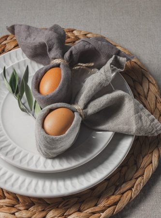 Festive Easter table setting. Funny Easter bunny made of eggs and linen napkin on plate. Gray background.の写真素材