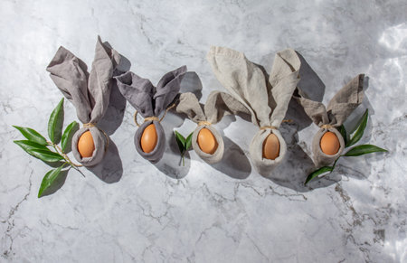 Festive Easter table setting. Funny Easter bunny made of egg and linen napkin on plate. gray background.の写真素材