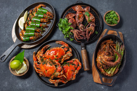 Set of Seafood Dishes. Crabs, octopus, squids and tiger shrimps on cast iron pans and plates on a black background. Top view.の写真素材