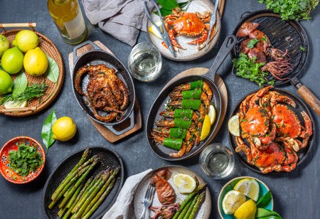 Set table with seafood dishes - cooked crabs, tiger shrimps, grilled octopus and squids on cast iron grilled pans and plates, White wine. Top viewの写真素材