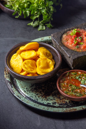 Sopaipilla. Latin American food. Traditional chilean homemade pumpkin sopaipillas with typical salsas - chancho en piedra tomato sauce in stone mortar and spicy pebreの写真素材