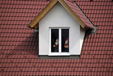 red tiled roof and dormer window with filthy garden gnomesの写真素材