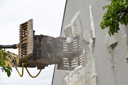 removing of Thermal insulation from the fronf of a residential house by a digger at the demolition