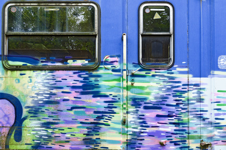 blue wall of an off service waggon with door and window, sprayed with colorful patternの写真素材