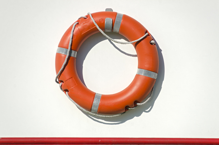 orange life bouy with rope on the white side wall of a shipの写真素材