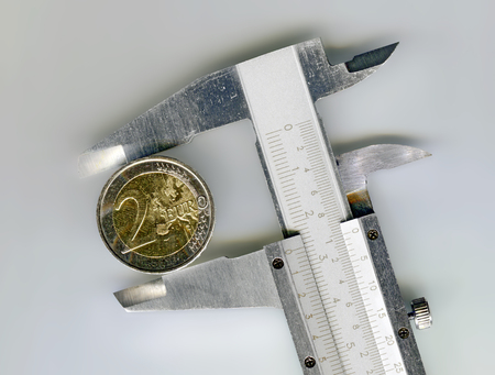 two euro coin between the large jaws of a sliding caliperの写真素材