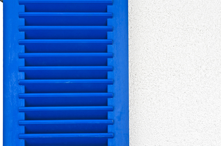 blue wooden  window shutter with slats on a white wallの写真素材