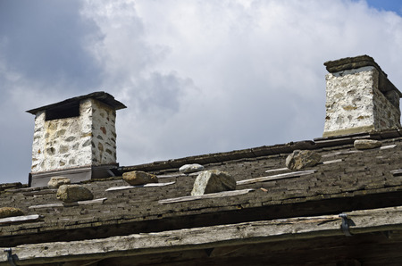 stone-built chimneys on a roof covered with shingles and weighted down with stonesの写真素材