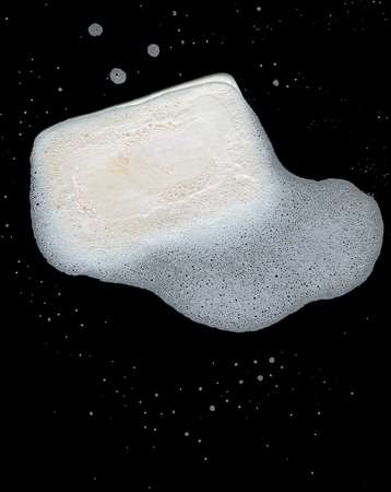 a piece of soap with white lather on black backgroundの写真素材