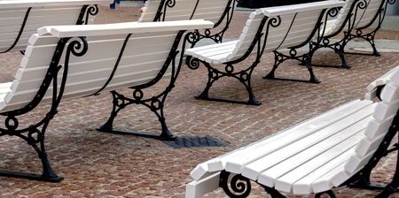 Park benches with white wooden seats and black iron frames on a promenadeの写真素材