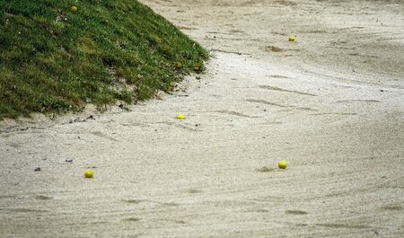 yellow balls in a sandy bunker of a golf courseの写真素材